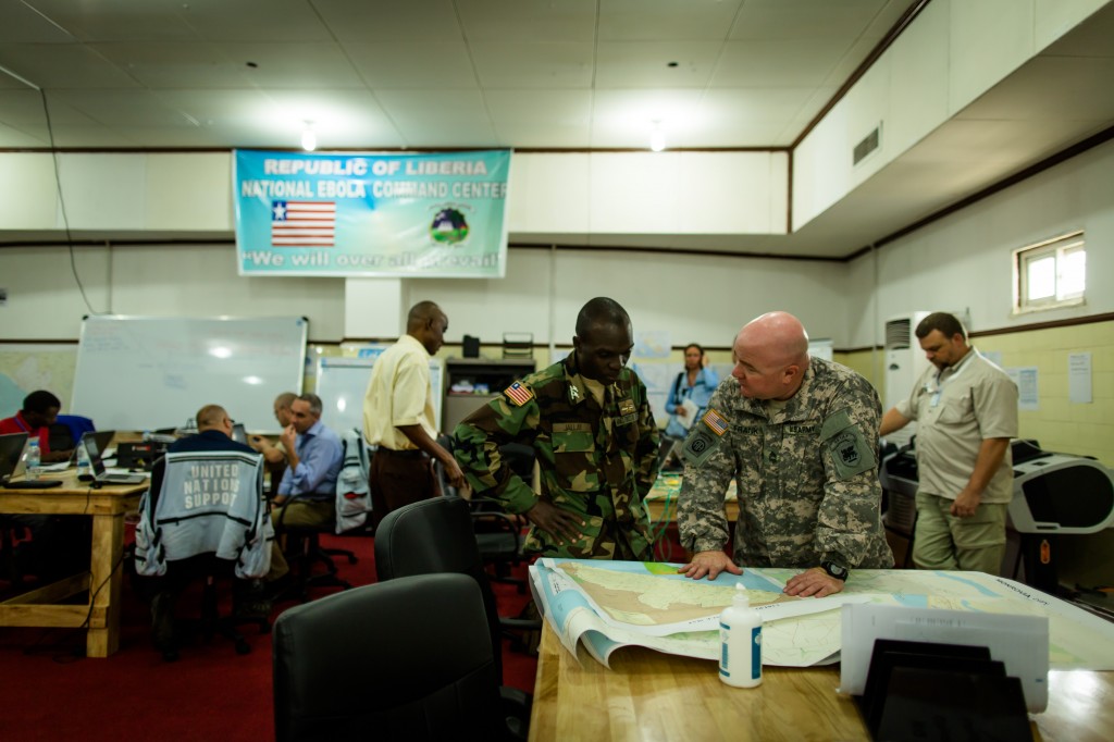 U.S. military personel review maps of Liberia with an Armed Forces of Liberia (AFL) soldier at the new Emergency Operations Center (EOC) for the Ebola response in Liberia