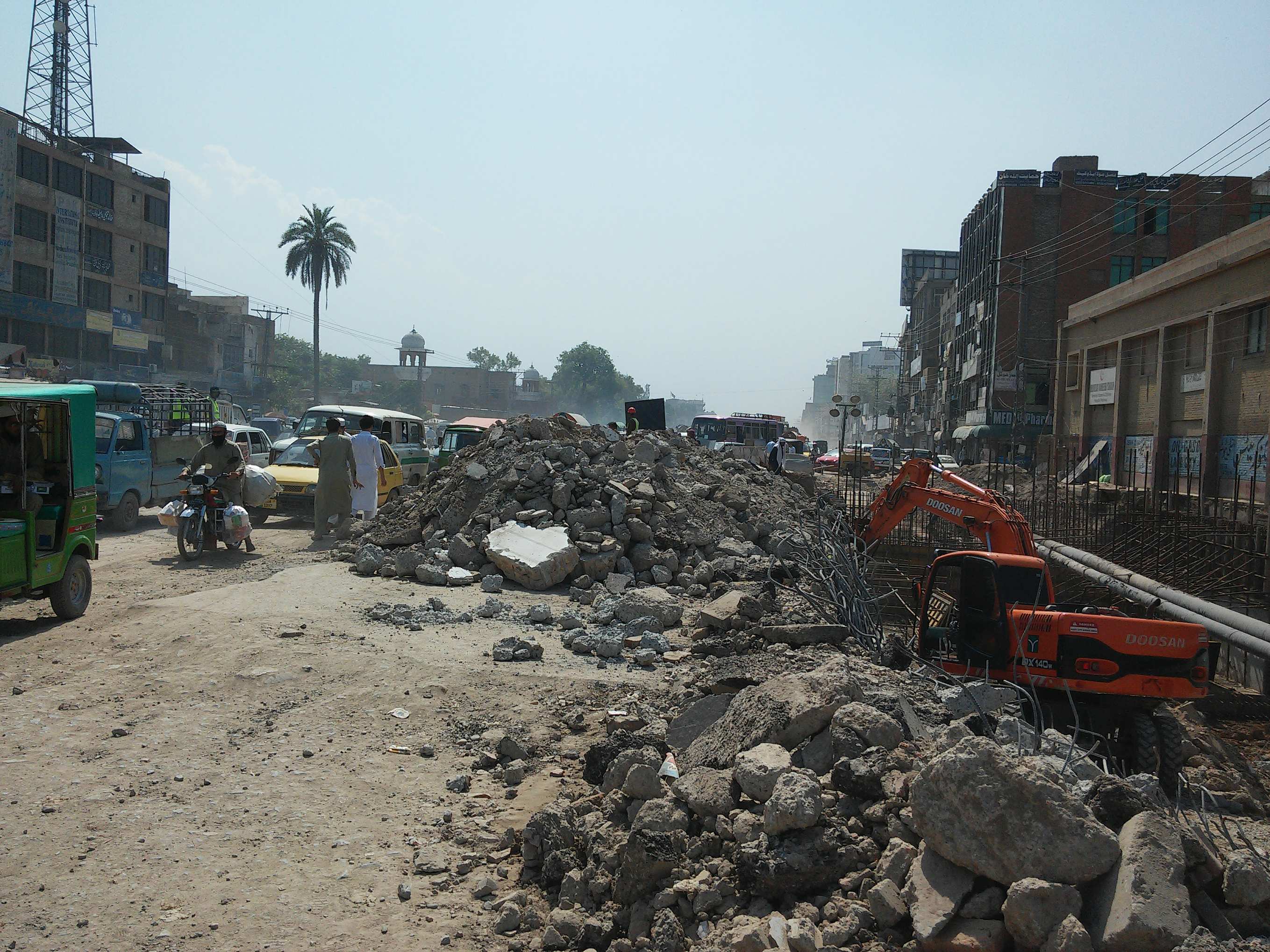 Motorist traveling along a poorly maintained road, exposed to building rubble, construction materials and machinery.