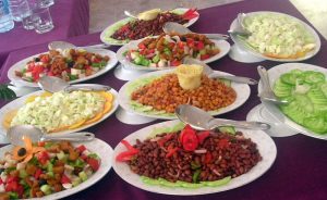 Nine dishes of vegetable based food on a purple clothed table