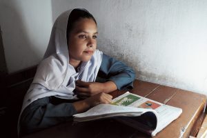 Girl in hijab looks over her workbook.