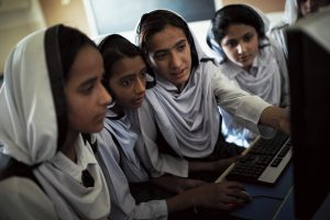 Girls in hijabs looking at a computer screen