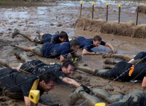 Tough Mudder particpants crawling through mud