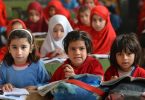 Three children sitting in a classroom in Pakistan.