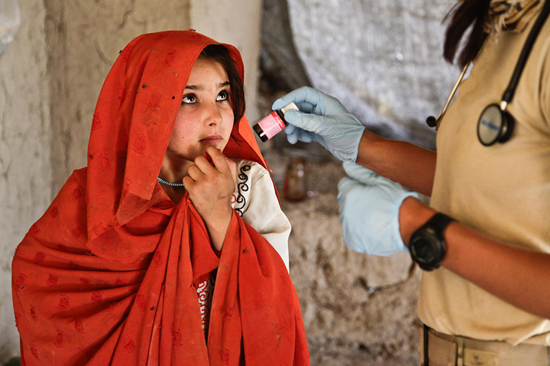 Young girl being handed a bottle by medical worker