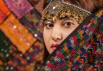 Close up of Pakistani woman dressed in traditional head-dress and colourful clothing.